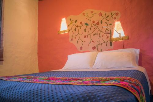 a bedroom with a bed with two lights on the wall at Hotel Campestre Solar De La Luna in Armenia