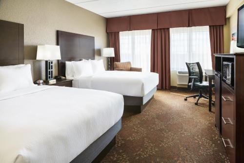 a hotel room with two beds and a desk at Holiday Inn Charlotte University by IHG in Charlotte