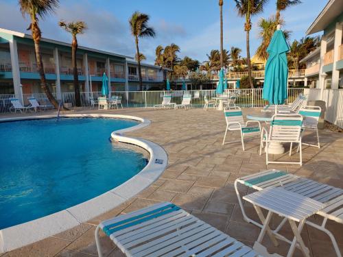 una piscina con sillas, una mesa y sombrillas en Sunrise Ocean Suites, en Pompano Beach