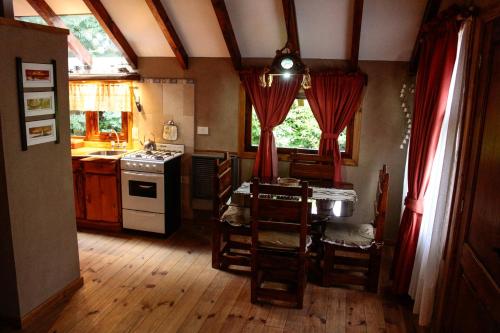 cocina con suelo de madera y cortinas rojas en Casa Del Sol en Villa La Angostura