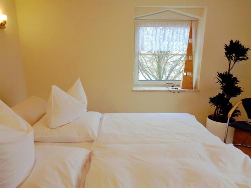 a bedroom with two white beds and a window at Gästehaus Schiemann in Teterow