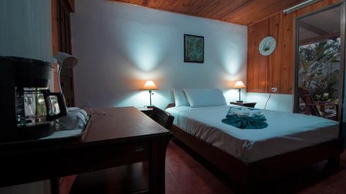 1 dormitorio con 1 cama y escritorio con 2 lámparas en Tirimbina Rainforest Lodge en Sarapiquí