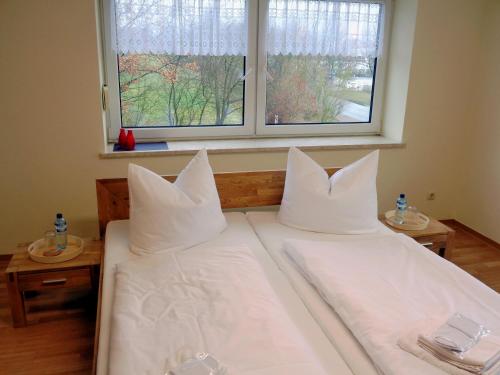 a bedroom with two beds with white pillows and a window at Gästehaus Schiemann in Teterow
