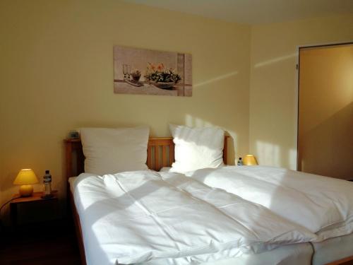 a bed with white sheets and pillows in a bedroom at Gästehaus Schiemann in Teterow