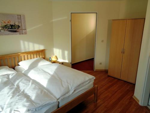a bedroom with a white bed and a closet at Gästehaus Schiemann in Teterow