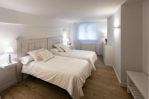 two beds in a bedroom with white walls and wood floors at Royalty, vivienda turística in Nájera