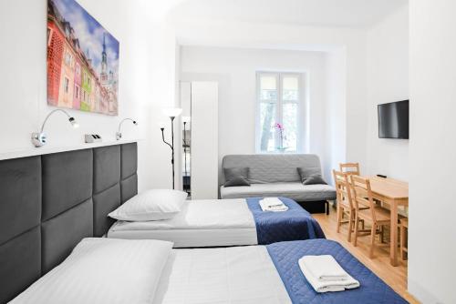 a bedroom with two beds and a table and a chair at Apartamenty Velvet in Poznań