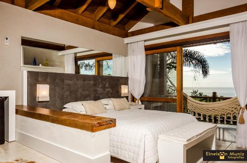 a bedroom with a bed and a balcony with a hammock at Solar Mirador Exclusive Resort e SPA in Praia do Rosa