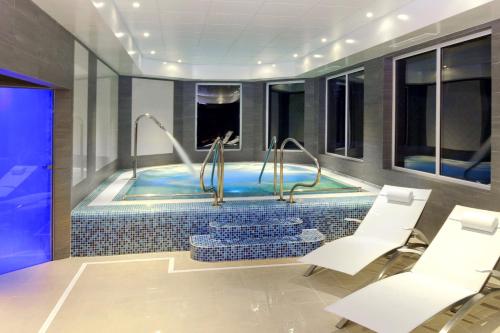 a pool in a room with white chairs and a table at Wickwoods Country Club Hotel & Spa in Albourne