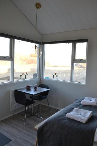 a bedroom with a bed and a table and windows at Ofanleiti Cottages in Vestmannaeyjar