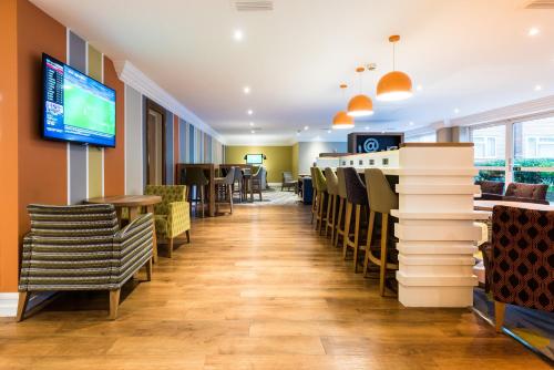 a restaurant with chairs and tables and a tv at Holiday Inn Chester South by IHG in Chester