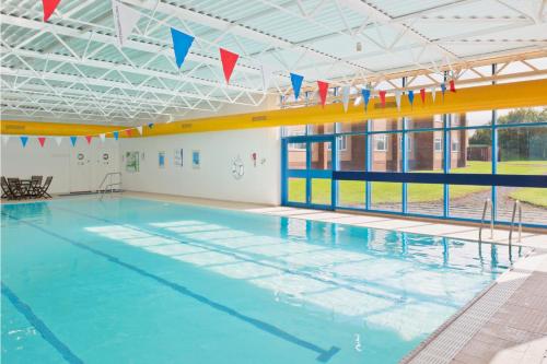 a large swimming pool with blue water and flags at Holiday Inn Chester South by IHG in Chester