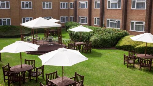an outdoor patio with tables and umbrellas in a courtyard at Holiday Inn Chester South by IHG in Chester
