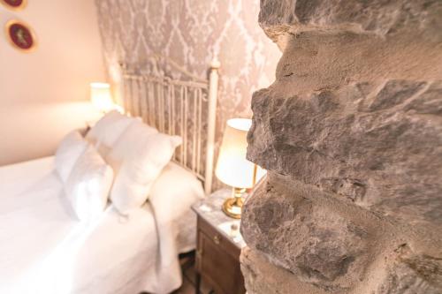a bedroom with a bed and a stone wall at Balcones con Encanto - vistas al conjunto monumental Patrimonio de la Humanidad in Úbeda