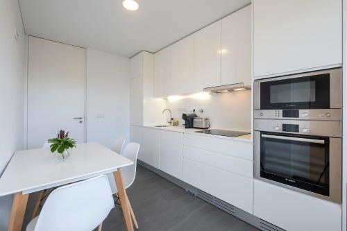 a white kitchen with white cabinets and a table at Green Island Beach Villa, Apartment in Ponta Delgada