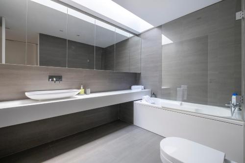 Un baño con lavabo, inodoro y espejo. en Green Island Beach Villa, Apartment, en Ponta Delgada
