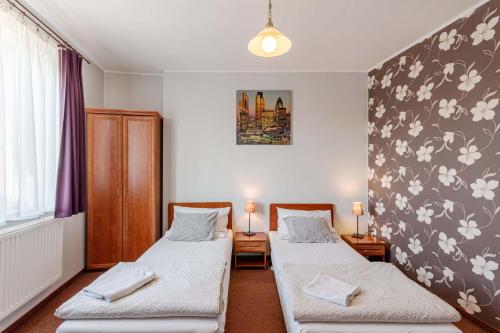 2 camas en una habitación con flores en la pared en Zajazd Bachus, en Dąbrowa Górnicza