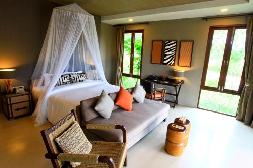 a bedroom with a bed and a chair and windows at Mountain Creek Golf Resort & Residences in Si Khio