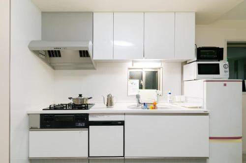Biała kuchnia z białymi szafkami i zlewem w obiekcie Osaka - House / Vacation STAY 74031 w Osace