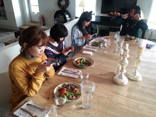a group of people sitting at a table looking at their cell phones at Brimslóð Atelier Guesthouse in Blönduós