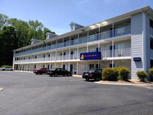 a large white building with cars parked in a parking lot at InTown Suites Extended Stay Charlotte NC - Albemarle in Charlotte