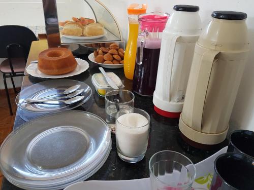 a table with plates of food and glasses of milk at Hotel Pousada Liberdade in Pindamonhangaba