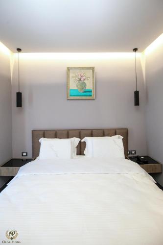 a bedroom with a large white bed with two pillows at Hotel Olive in Vlorë