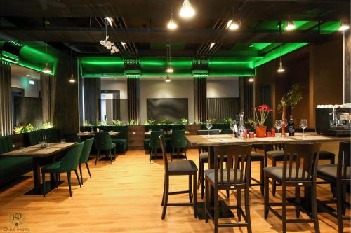 a restaurant with green lighting and tables and chairs at Hotel Olive in Vlorë