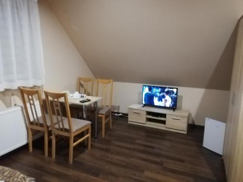een woonkamer met een televisie en een tafel met stoelen bij Pokoje gościnne Alicja in Kudowa-Zdrój