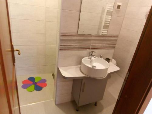 a white bathroom with a sink and a mirror at Appartment 2 in Braşov