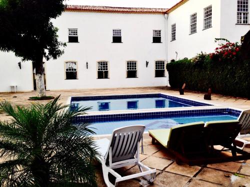 a swimming pool with two chairs and a house at Pousada Convento do Carmo in Cachoeira