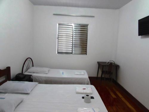 a white room with two beds and a window at Teodoro Palace Hotel a 5 minutos do Brás e Bom Retiro in Sao Paulo