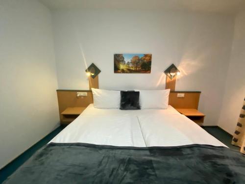 a bedroom with a bed with white sheets and pillows at Landhotel Rauber Sankt Wendel in Oberthal
