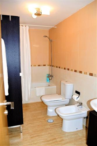 a bathroom with two toilets and a sink and a tub at Gecko in Tazacorte