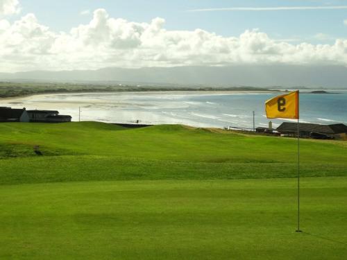 a yellow sign on a golf course next to the ocean at The Old School in Ballyheigue