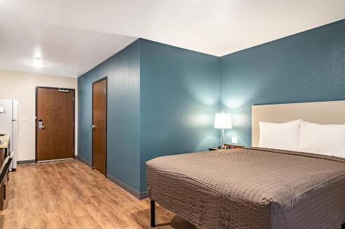 a bedroom with a bed and a blue wall at WoodSpring Suites Toledo Maumee in Maumee