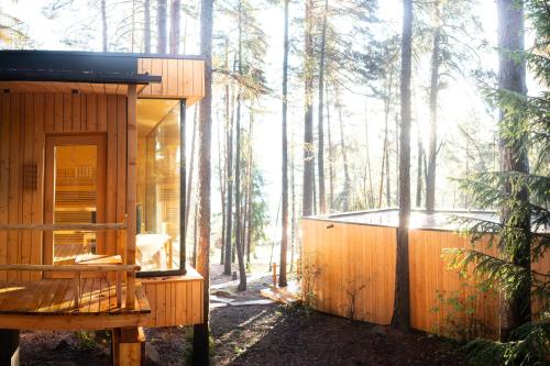 a wooden cabin in the woods with the sun shining through the trees at ADLER Lodge RITTEN in Soprabolzano