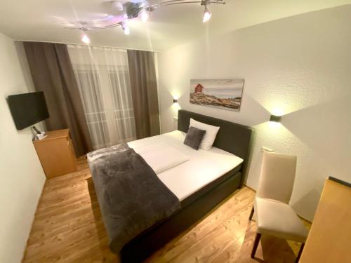a small bedroom with a bed and a chair at Landhotel Rauber Sankt Wendel in Oberthal