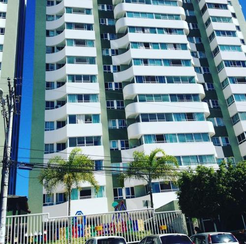 um edifício de apartamentos alto com carros estacionados em frente em Apartamento mobiliado - Salvador em Salvador