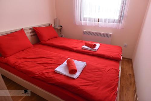 - un lit avec des draps rouges et des oreillers rouges dans l'établissement Apartman Ledjanac, à Zlatibor