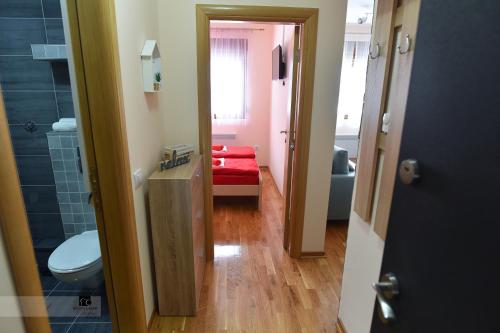 La salle de bains est pourvue de toilettes et d'un banc rouge. dans l'établissement Apartman Ledjanac, à Zlatibor