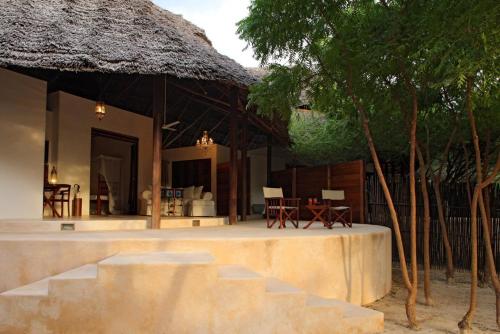a house with a thatched roof and stairs leading to it at The Red Pepper House in Lamu