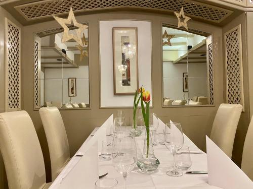 a dining room with a table with a vase of flowers at Landhotel Rauber Sankt Wendel in Oberthal
