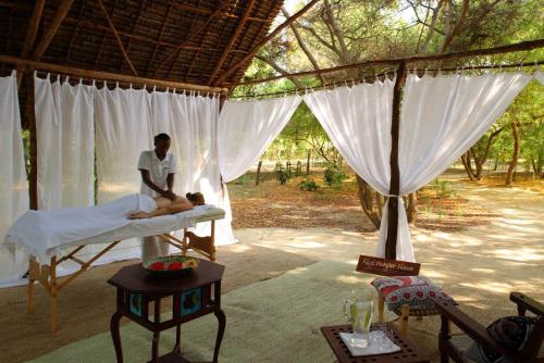 a man sitting on a bed in a tent with a baby at The Red Pepper House in Lamu