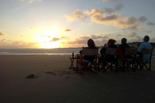 a group of people sitting on the beach watching the sunset at The Red Pepper House in Lamu