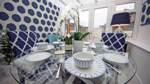 una sala da pranzo con tavolo in vetro e sedie blu di Moryn. Snowdonia and Anglesey View a Bangor