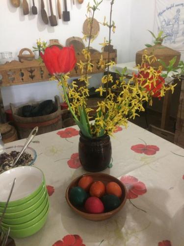 a table with a bowl of eggs and a vase with flowers at Falubíró Vendégháza in Bekölce