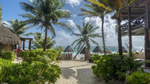 a beach with palm trees and the ocean at La Conchita Tulum in Tulum