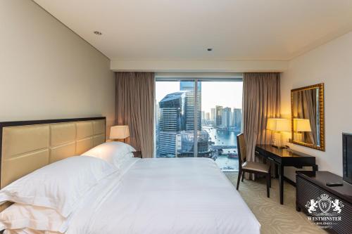 a hotel room with a bed and a desk and a window at Westminster Dubai Marina in Dubai