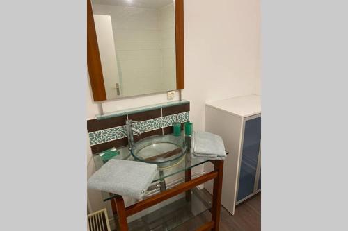 La salle de bains est pourvue d'un lavabo en verre et d'un miroir. dans l'établissement Appartement 300m Plage, à Dunkerque